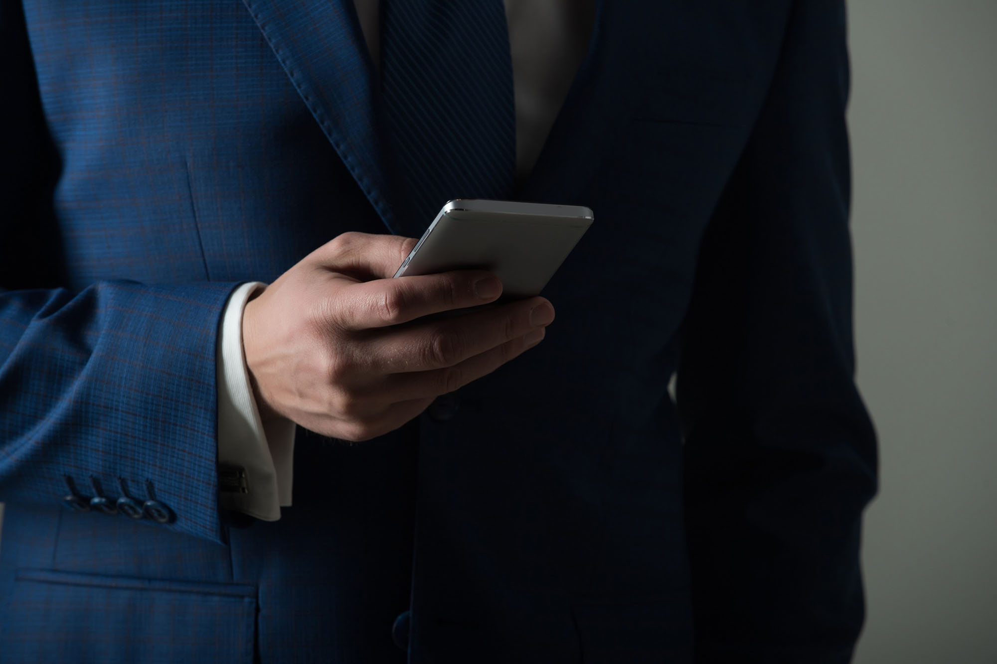 A man in a business suit holding a mobliephone